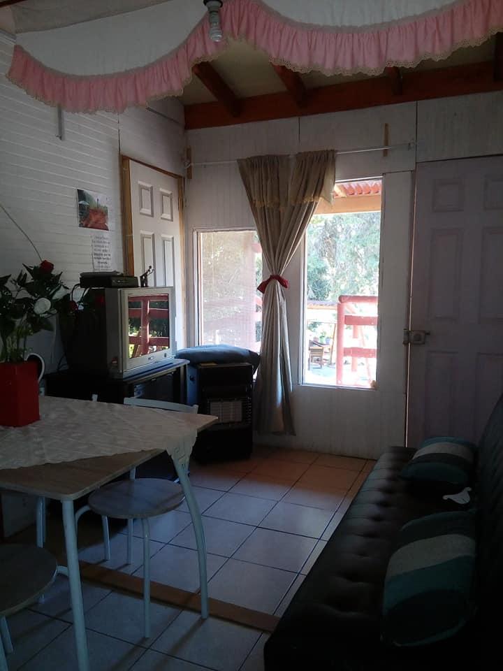 Interior de cabaña con mesa de comedor y sofá
