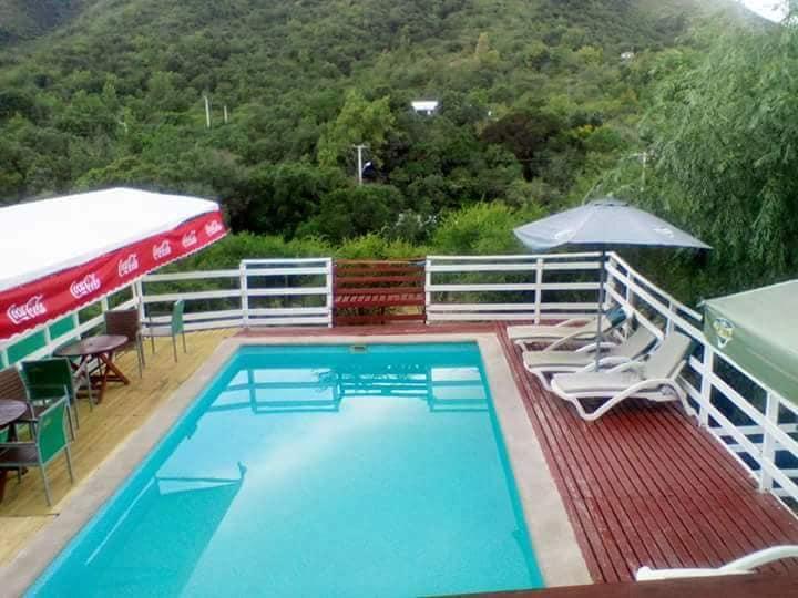 Piscina exterior con reposeras y cerros arbolados